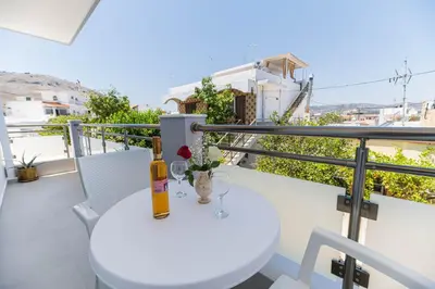 a white table with a bottle and glasses on a balcony at Antonis Studio in Archangelos