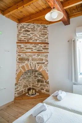 a room with a brick fireplace with two beds at Marianthi's House in Émbonas