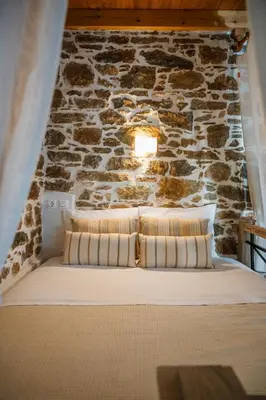 a bed in a room with a stone wall at Marianthi's House in Émbonas
