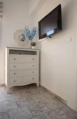 a dresser with a flat screen tv on a wall at Le Petit Refuge 2 Floor Maisonette with Seaview in Archangelos