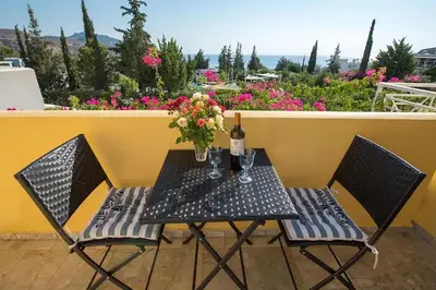 a table with two chairs and a bottle of wine and flowers at Le Petit Refuge 2 Floor Maisonette with Seaview in Archangelos