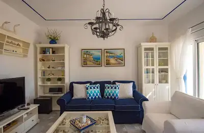 a living room with a blue couch and a chandelier at Le Petit Refuge 2 Floor Maisonette with Seaview in Archangelos
