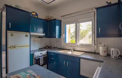 a kitchen with blue cabinets and a white refrigerator at Le Petit Refuge 2 Floor Maisonette with Seaview in Archangelos