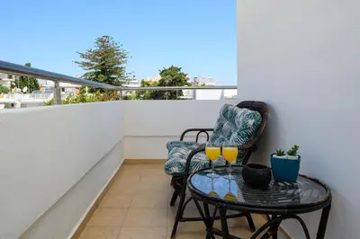 a balcony with two chairs and a glass table at Emerald City Apartment in Rhodes Town