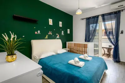 a green bedroom with a bed with towels on it at Emerald City Apartment in Rhodes Town