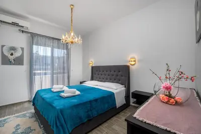 a bedroom with a bed with blue sheets and a chandelier at Emerald City Apartment in Rhodes Town
