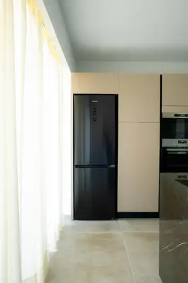 a black refrigerator in a kitchen with white curtains at Mairyloy city luxury apartment in Rhodes Town