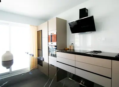 a kitchen with white cabinets and a tv on the wall at Mairyloy city luxury apartment in Rhodes Town