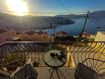 a table and chairs on a balcony with a view of the water at Duchess Harbour View in Symi