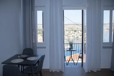 a room with a table and chairs and a balcony at Duchess Harbour View in Symi