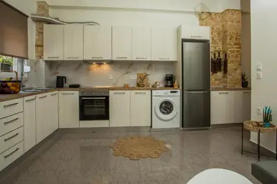 a kitchen with white cabinets and a washer and dryer at Filoxenia house in Kremasti