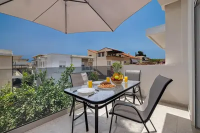 a dining table and chairs on the balcony of a house at Andreas Rodos Apartment in Rhodes Town