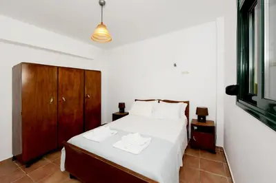 a bedroom with a white bed and a wooden cabinet at Seaside Villa in Gennadi