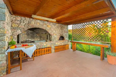 an outdoor patio with a stone fireplace and a table at Olive Private Villa Swimming Pool 5 BDR Kolymbia Rhodes in Kolimbia