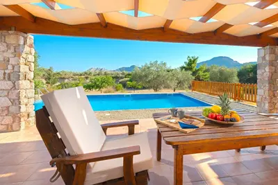 a patio with a table and a chair and a pool at Olive Private Villa Swimming Pool 5 BDR Kolymbia Rhodes in Kolimbia