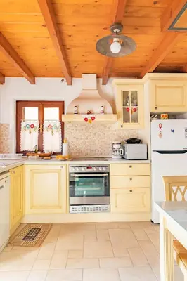 a kitchen with white appliances and a wooden ceiling at Kampos House in Symi