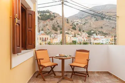 a table and two chairs on a balcony with a view at Kampos House in Symi