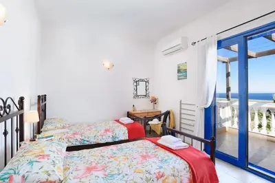a bedroom with a bed and a view of the ocean at Villa Elysium in Kalathos