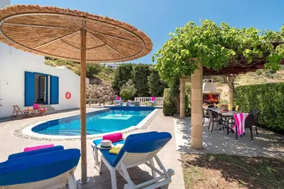 a pool with chairs and a table and an umbrella at Villa Elysium in Kalathos