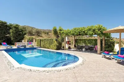 a swimming pool in a yard with chairs and an umbrella at Villa Elysium in Kalathos