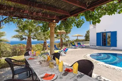 a patio with a table and chairs and a swimming pool at Villa Elysium in Kalathos