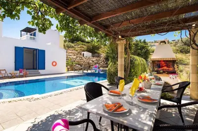 a table with food on it next to a swimming pool at Villa Elysium in Kalathos