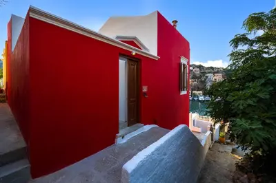 a red house with a red wall at Annikas Port View-1st Floor in Symi