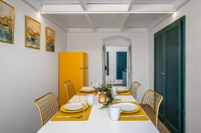 a dining room with a white table and chairs at Annikas Port View-1st Floor in Symi