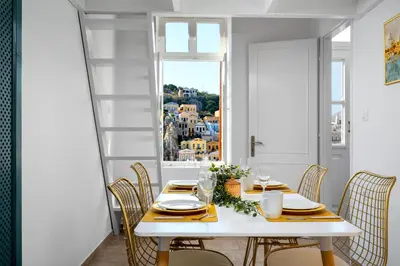 a white dining room with a table and chairs and a window at Annikas Port View-1st Floor in Symi
