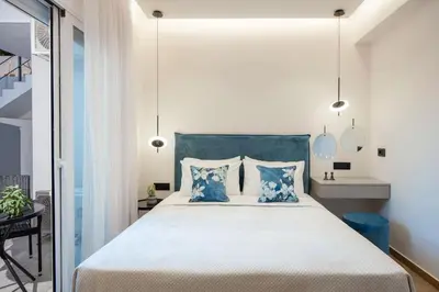 a bedroom with a large bed with blue pillows at Santa Marina Luxury Apartments #2 with pool in Asgourou
