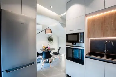a kitchen with white cabinets and a table with chairs at Santa Marina Luxury Apartments #2 with pool in Asgourou