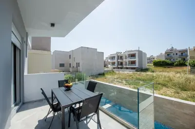 a balcony with a table and chairs on a balcony at Santa Marina Luxury Apartments #2 with pool in Asgourou