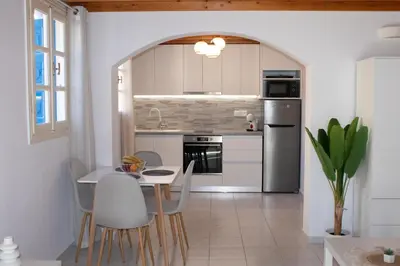 a kitchen with white cabinets and a table and chairs at Duchess House in Symi