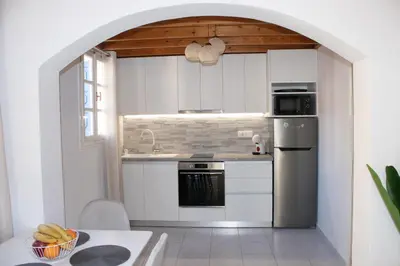 a kitchen with white cabinets and a sink and a stove at Duchess House in Symi