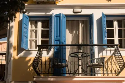 a balcony with two chairs and blue windows at Duchess House in Symi