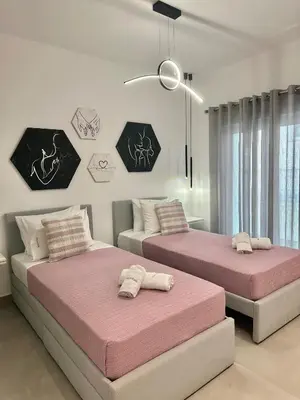 two beds in a bedroom with pink sheets at Nice n Cosy Apartment II in Rhodes Town