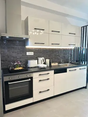 a kitchen with white cabinets and a stove top oven at Nice n Cosy Apartment II in Rhodes Town
