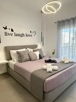 a bedroom with a large bed with words live laugh love at Nice n Cosy Apartment II in Rhodes Town
