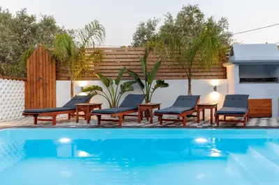 a swimming pool with lounge chairs and a fence at Alamia Suites in Archangelos