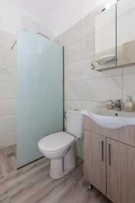 a white bathroom with a toilet and a sink at Alamia Suites in Archangelos