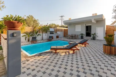 a backyard with a swimming pool and a house at Alamia Suites in Archangelos