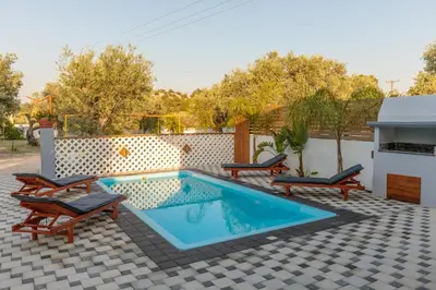 a pool with chaise lounge chairs and a swimming pool at Alamia Suites in Archangelos