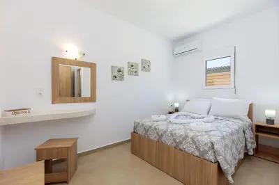 a white bedroom with a bed and a mirror at Alamia Suites in Archangelos