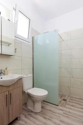 a bathroom with a toilet and a sink and a shower at Alamia Suites in Archangelos