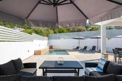 a patio with two couches and a table with an umbrella at Villa Olea in Archipolis