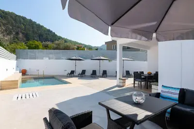 a patio with a table and chairs and an umbrella at Villa Olea in Archipolis