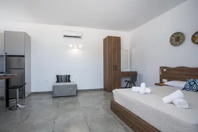 a bedroom with a bed and a desk and a kitchen at Faliraki Harmony Apartments in Faliraki