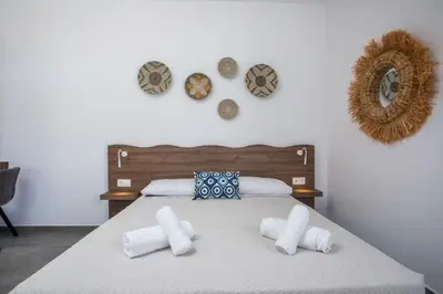 a bedroom with a bed with white sheets and pillows at Faliraki Harmony Apartments in Faliraki