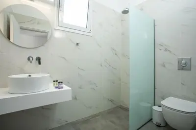 a white bathroom with a sink and a mirror at Faliraki Harmony Apartments in Faliraki