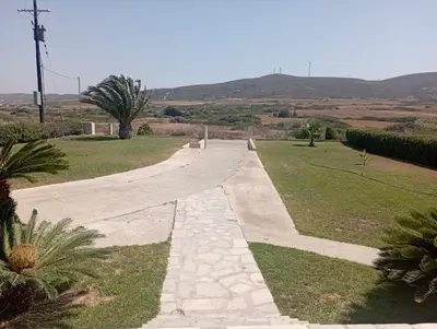 a walkway in a field with palm trees and mountains at Katavias House in Kattavía